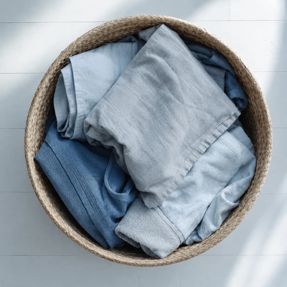 A round laundry basket seen from directly above, loosely filled with pale folded textile.