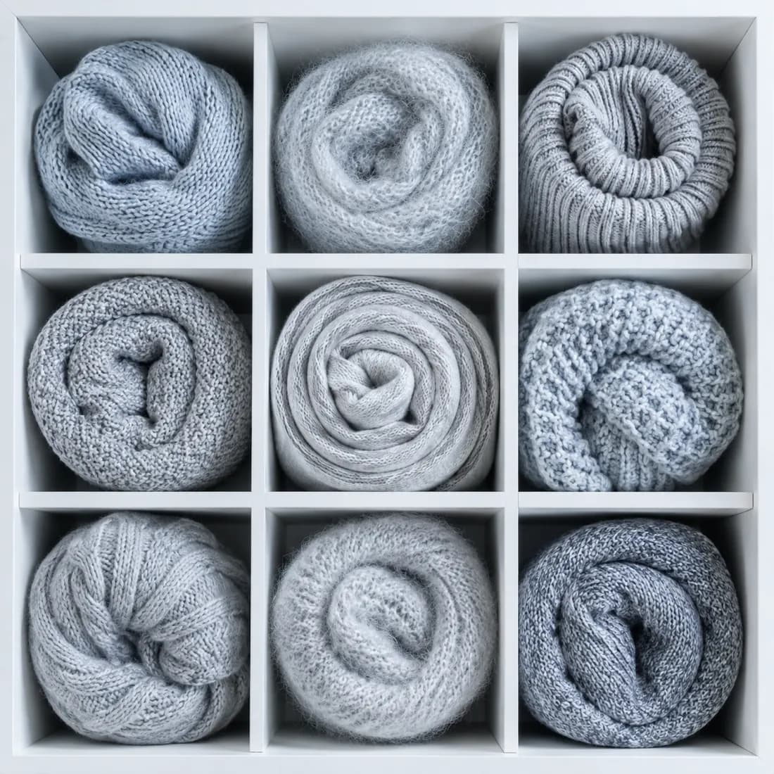 A grid of nine square drawer compartments seen from above, each holding a differently textured roll.